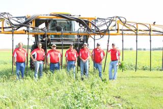 Members of soil health team standing in field in front of farming machine
